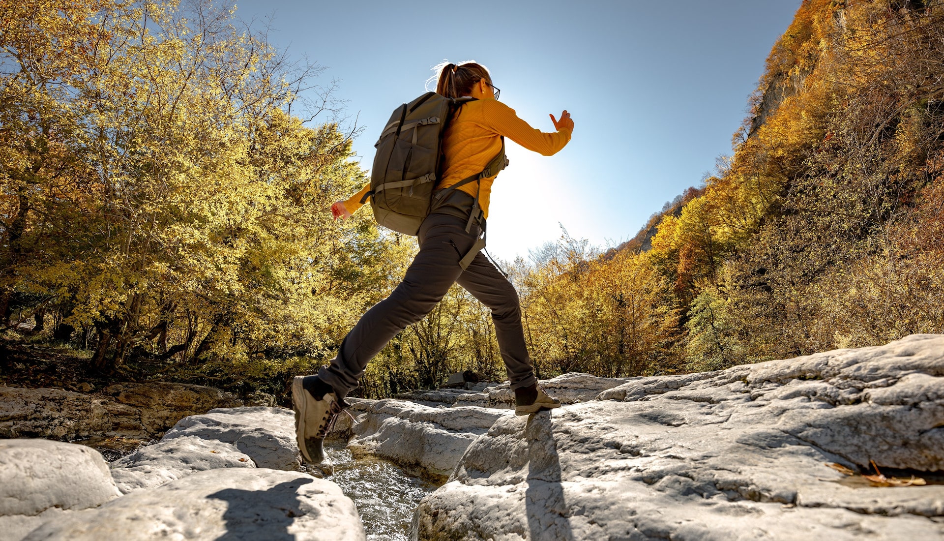 Junge Dame mit Rucksack schnellen Schrittes auf einer Wanderung im Herbst